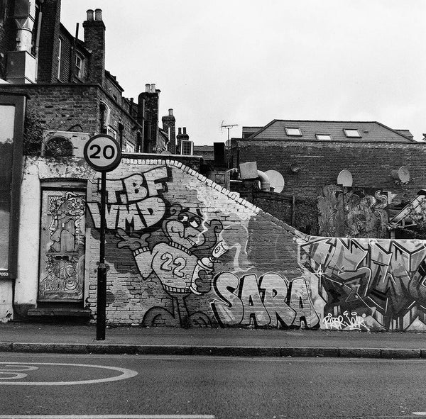 A broken wall with graffiti in black and white.