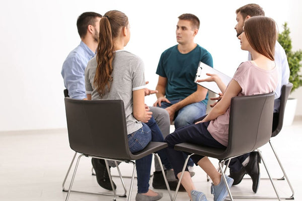 A group of individuals gathered for transgender consultation and therapy, engaged in a discussion and supporting each other.
