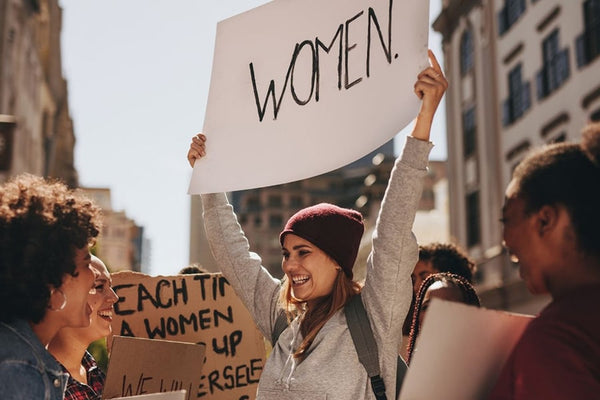 Empowered woman at LGBTQ-supportive feminist rally, holding a 'Women's Rights' sign, advocating for gender equality and inclusivity.