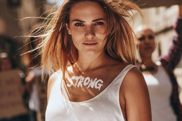 Una mujer rubia de pelo largo, segura y orgullosa, que participa en una protesta feminista, defiende la igualdad de género y aboga por la educación feminista.