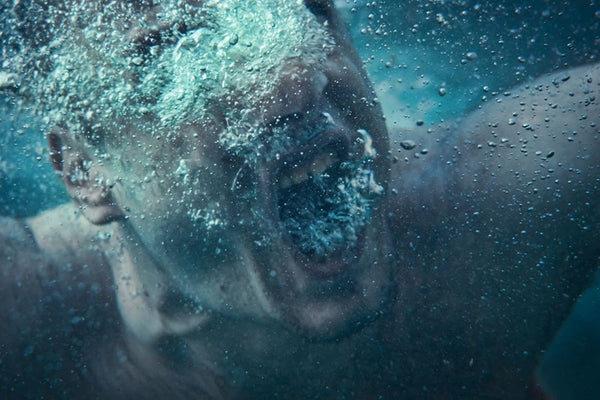 A non-binary androgynous tomboy experiencing difficulty breathing underwater, urgently seeking assistance in a potentially dangerous situation.