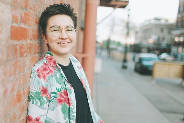 A transgender male in a portrait, facing the camera on a sunny day in a New York street.