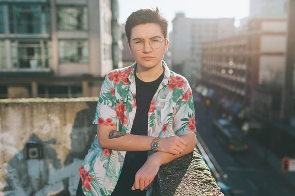 A transgender male in a portrait, facing the camera on a sunny day in a New York street.