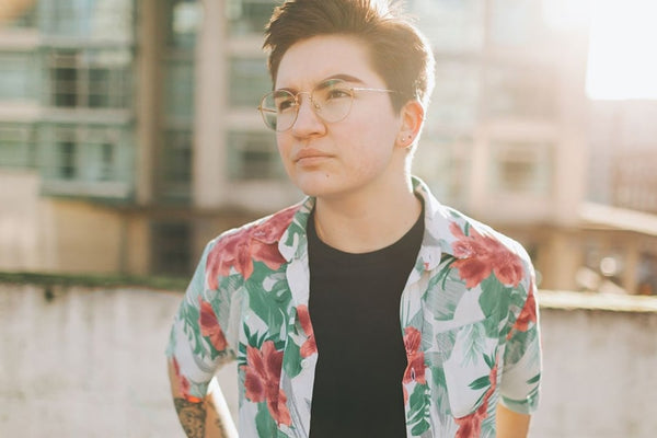 A transgender male in a portrait, facing the camera on a sunny day in a New York street.