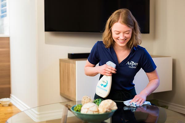 AspenClean professional cleaner is using the AspenClean glass cleaner and cloth kit to clean the table