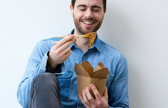 A man is eating the take out noodles 