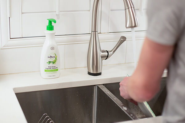 a man is washing the dishes with AspenClean Natural Dish Soap Eucalyptus and Rosemary