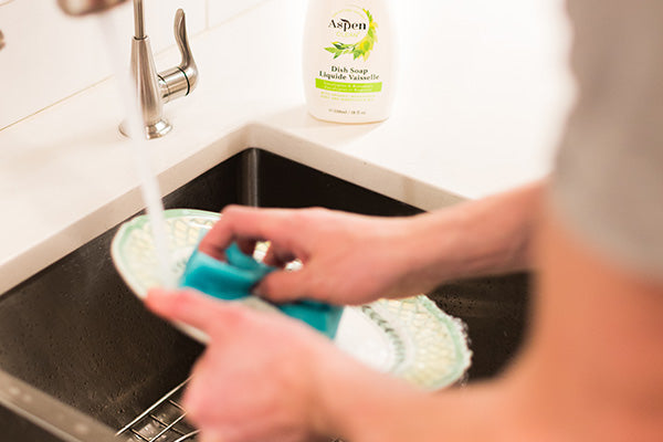 The man is doing the dishes by using AspenClean Natural Dish Soap