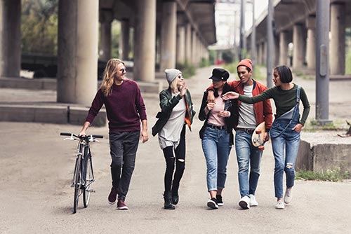 5 young adults are chatting and walking on the street 