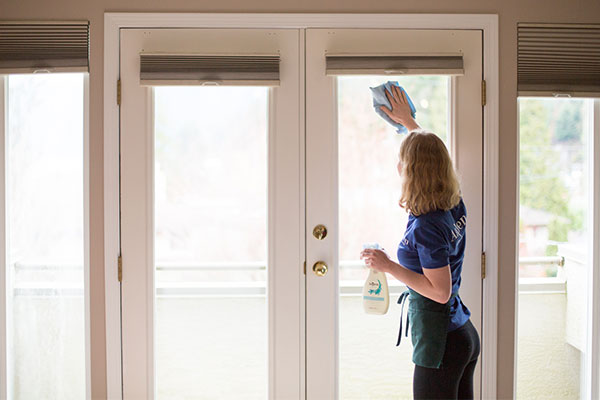 AspenClean professional cleaner is wiping the window with Natural Glass Cleaner and the cloth during move in cleaning service 