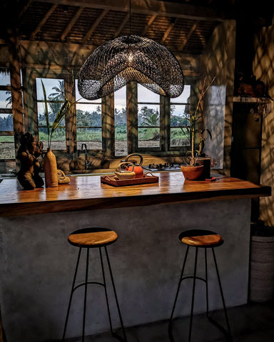 Large black rattan lampshade over tropical kitchen island at sunrise