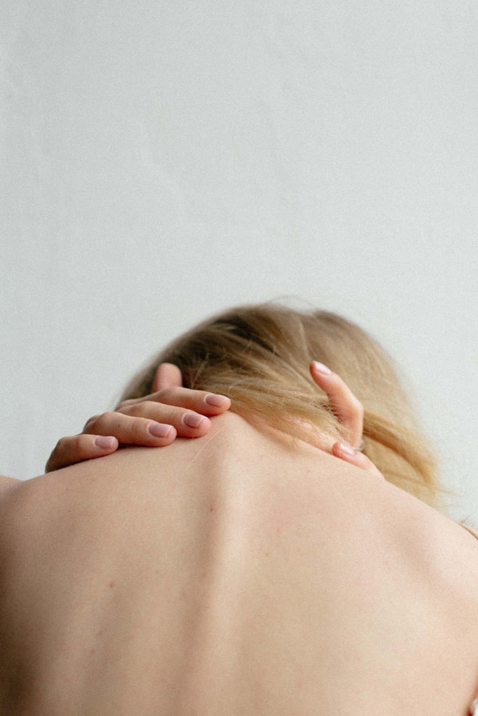 causas del dolor de espalda mujer sosteniendo la cabeza hacia abajo con dolor