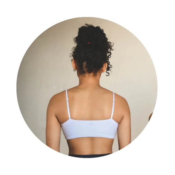 The back of a young girl wearing a white Bleum Petal Padded Bra from the Bleuet website.