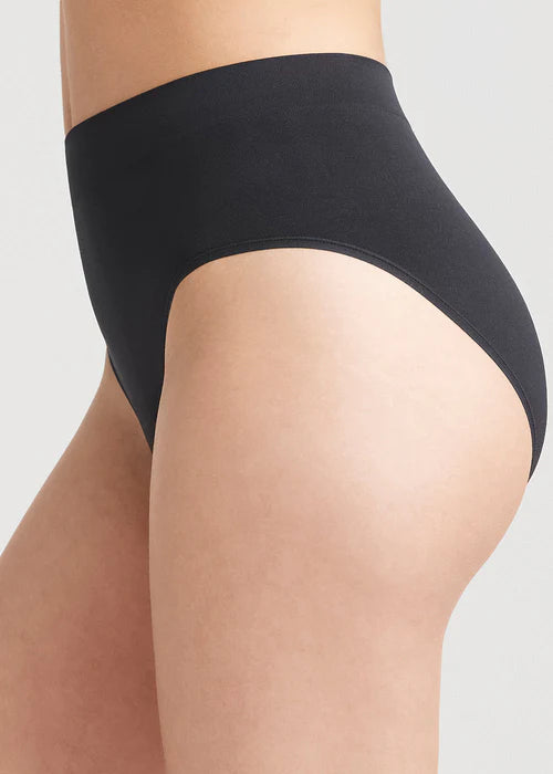 non-shaping retro brief - seamless in Black worn by a woman standing sideways Yummie