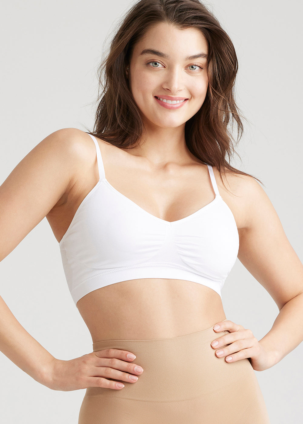 V-Neck Bralette – Seamless in White worn by woman facing forward with hands on hip Yummie