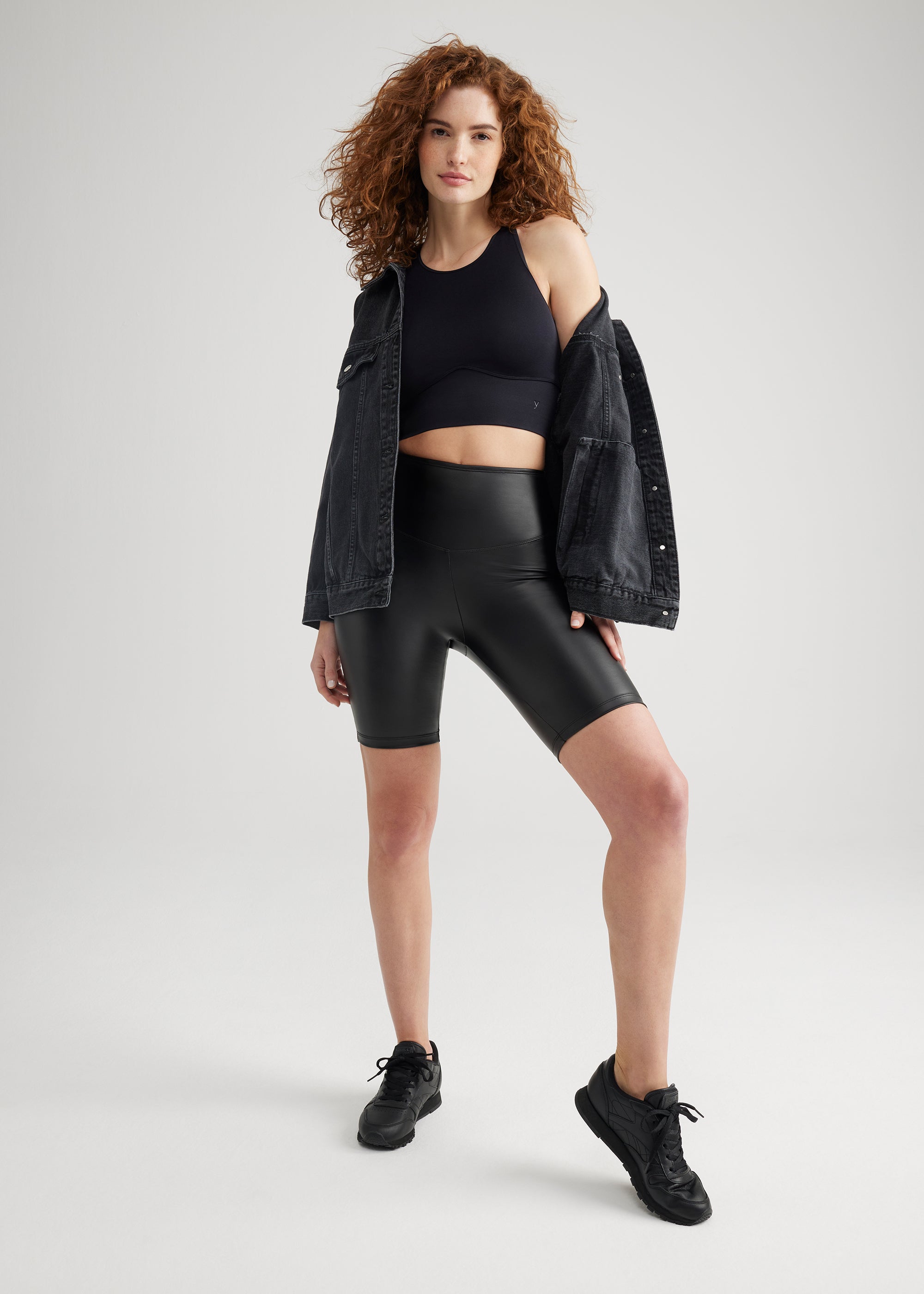 kelly high-neck longline bra top - seamless, Faux Leather Shaping Biker Short and denim jacket in Black  worn by a woman standing facing forward with one leg bent and arms at side Yummie