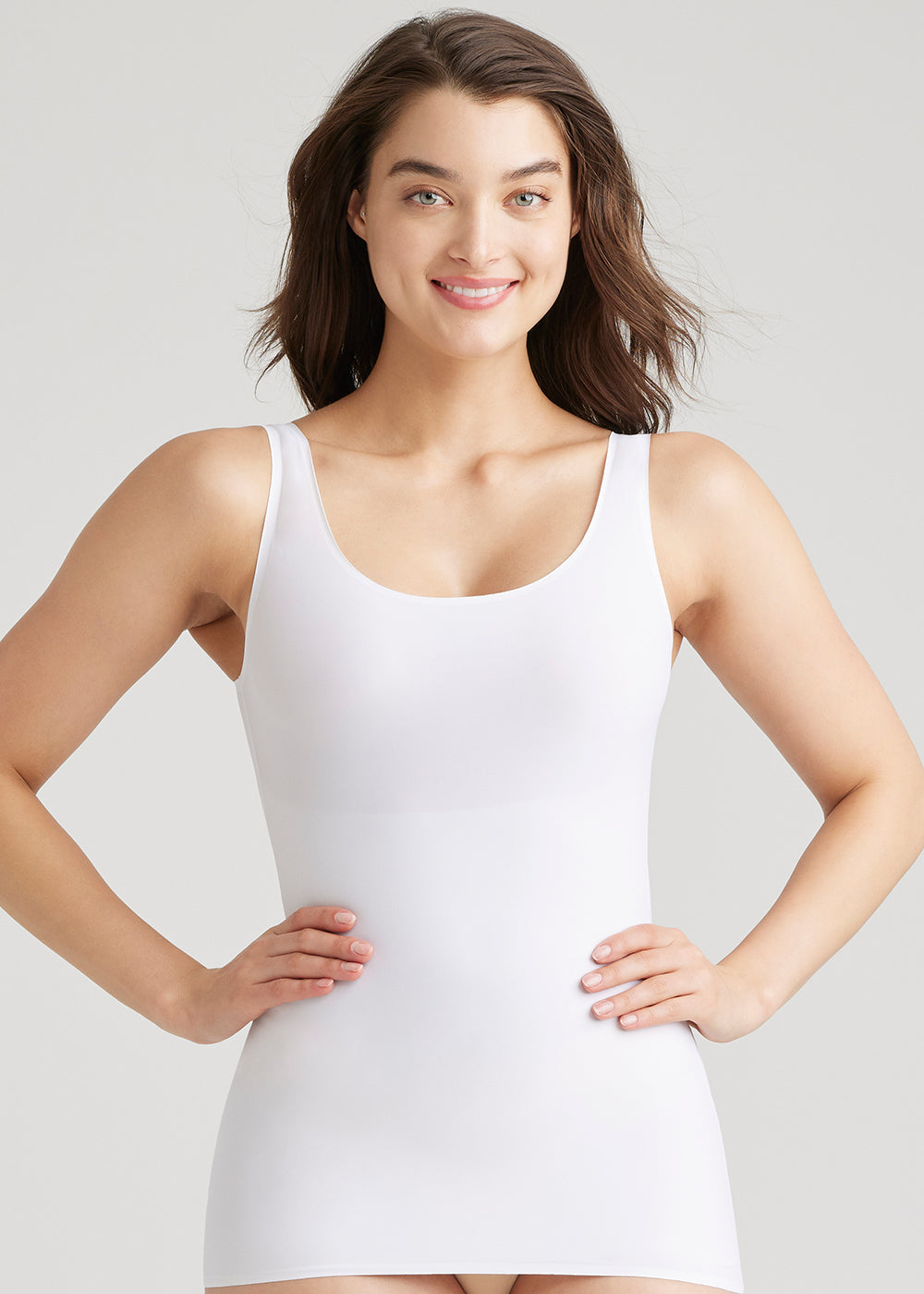 6-in-1 shaping tank in white worn by a woman standing smiling with her hands on her hips