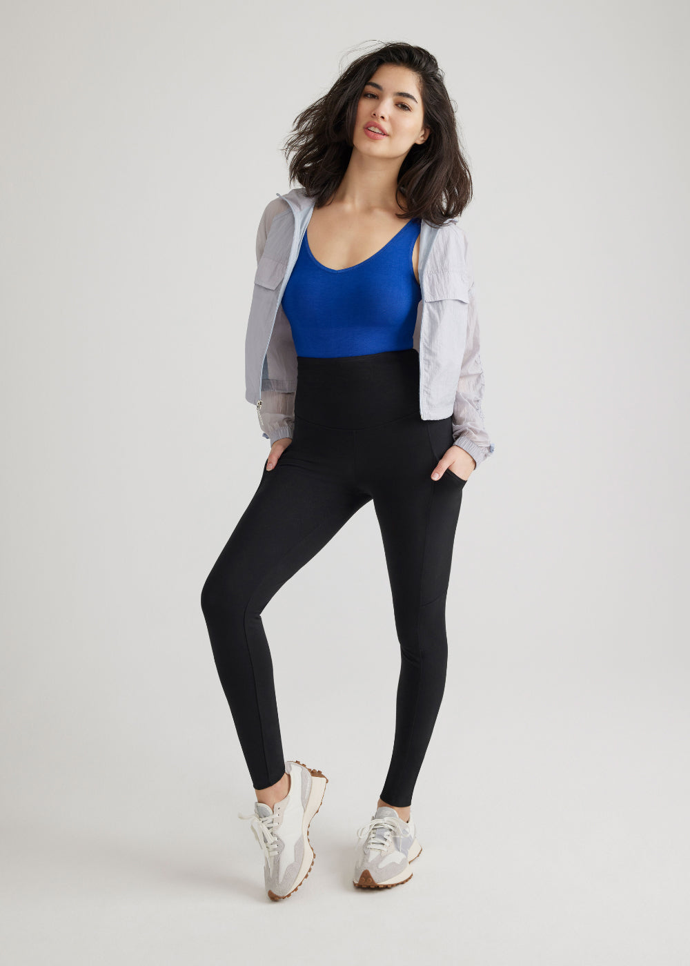 rachel shaping legging with side pockets - cotton stretch in Black and 2-way shaping tank - outlast® seamless in Sodalite Blue worn by a woman standing facing forward with right leg bent and hands in pockets Yummie