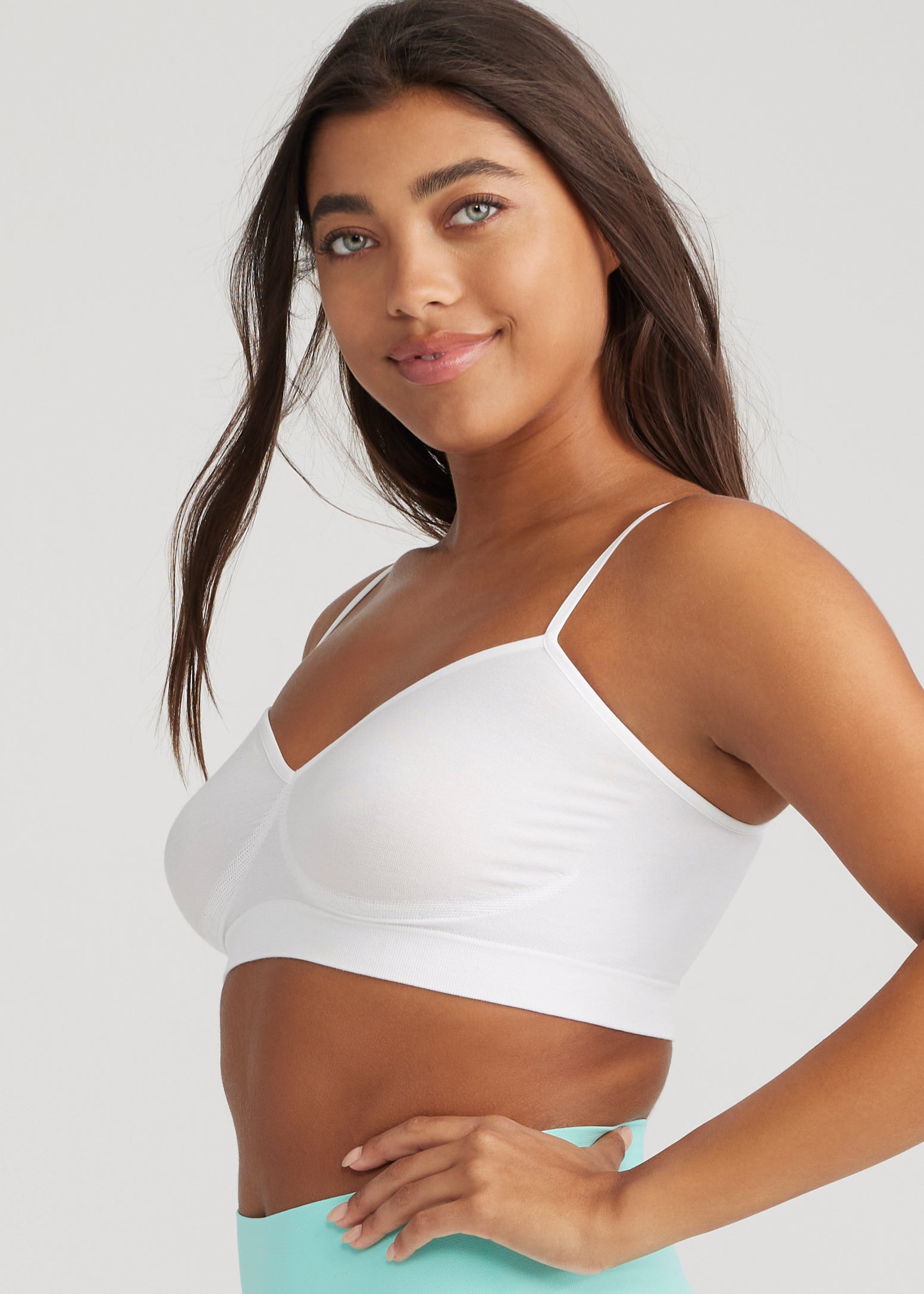 audrey unlined bralette - outlast® seamless in White  worn by a woman standing sideways with left hand on waist Yummie