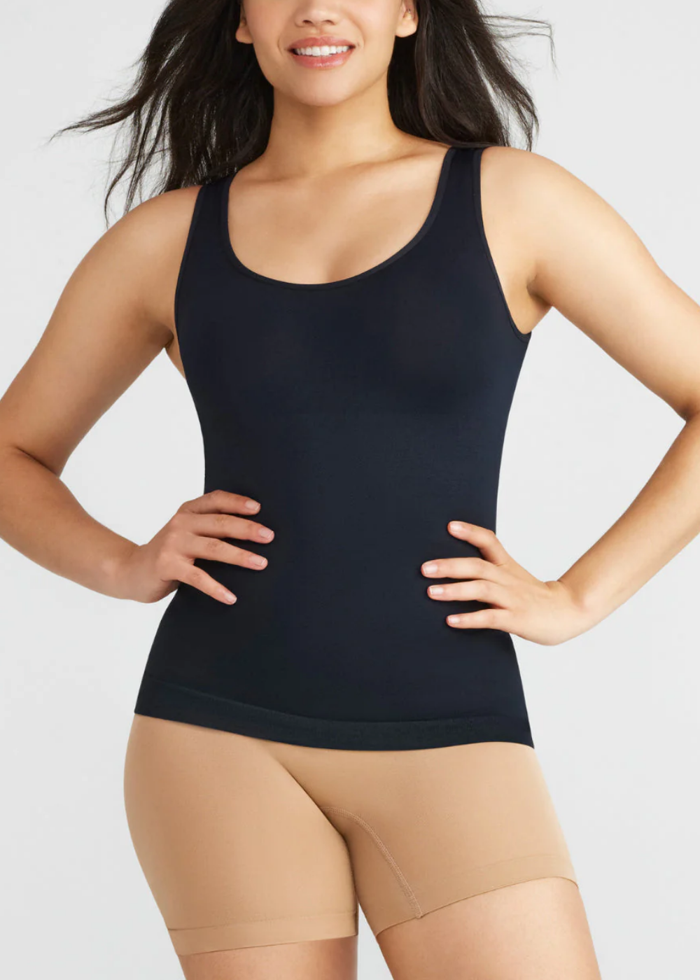 lena shaping tank - seamless in black worn by a woman standing with both hands on her hips