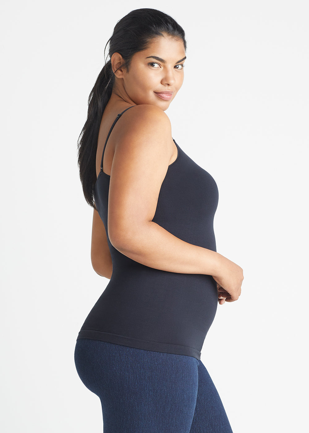 convertible shaping camisole - outlast® seamless in Black and denim shaping legging in True Indigo worn by a woman standing sideways with arms at waist Yummie