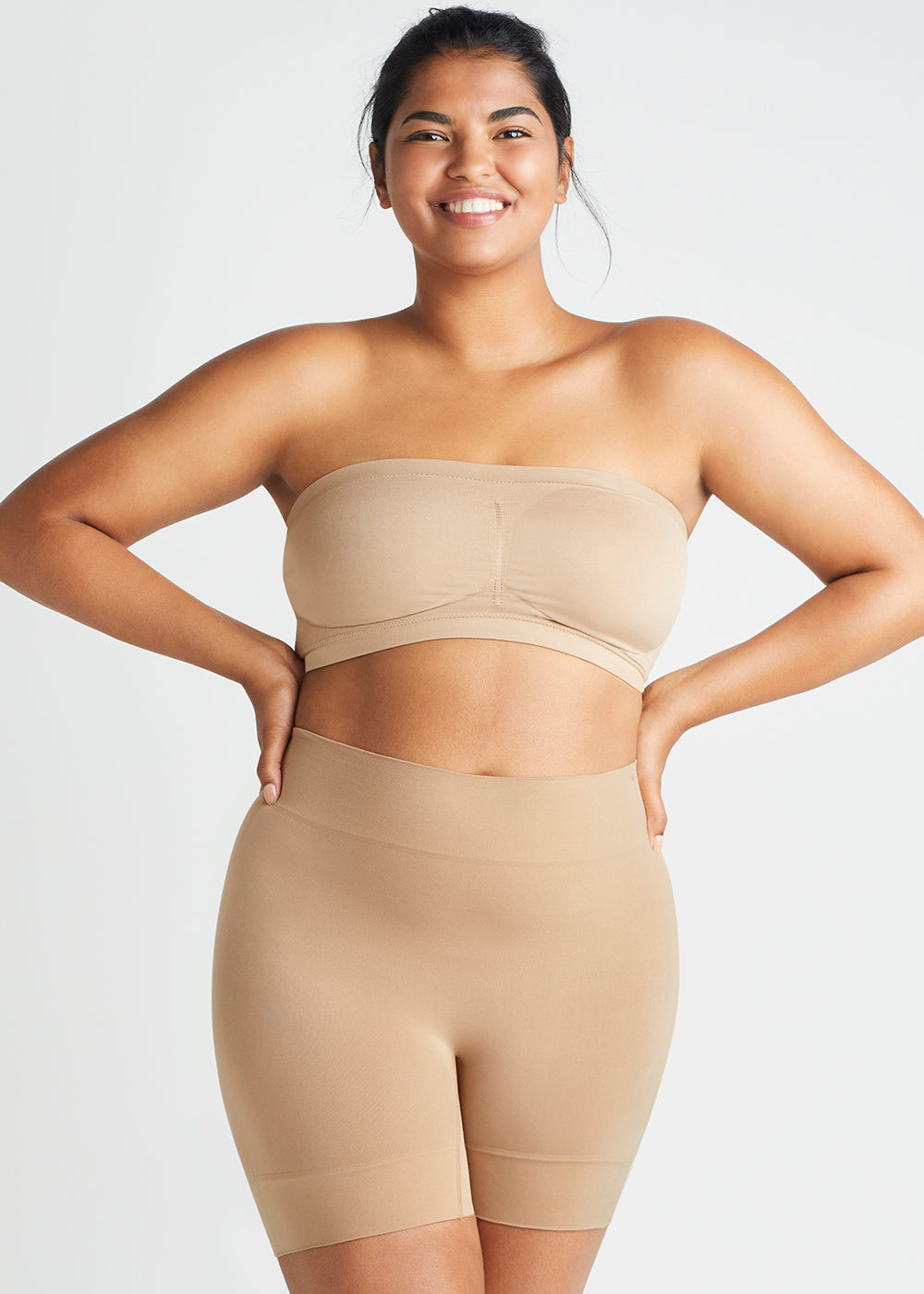 bria comfortably curved smoothing short - seamless and bandeau bra – seamless in Almond worn by woman with hands on hips facing forward Yummie