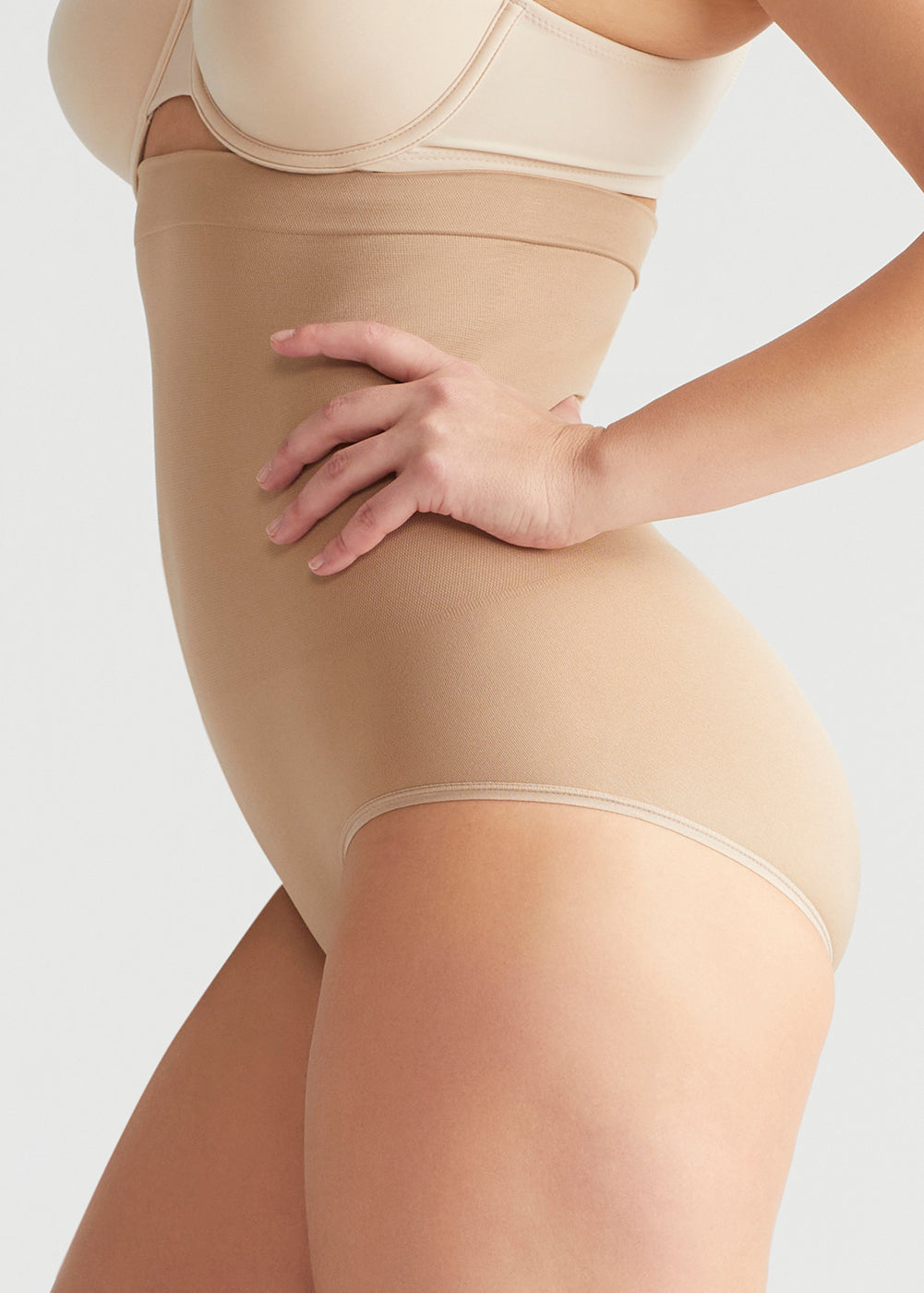 seamless solutions - high waist shaping brief in Almond worn by woman with hand on hip side view Yummie