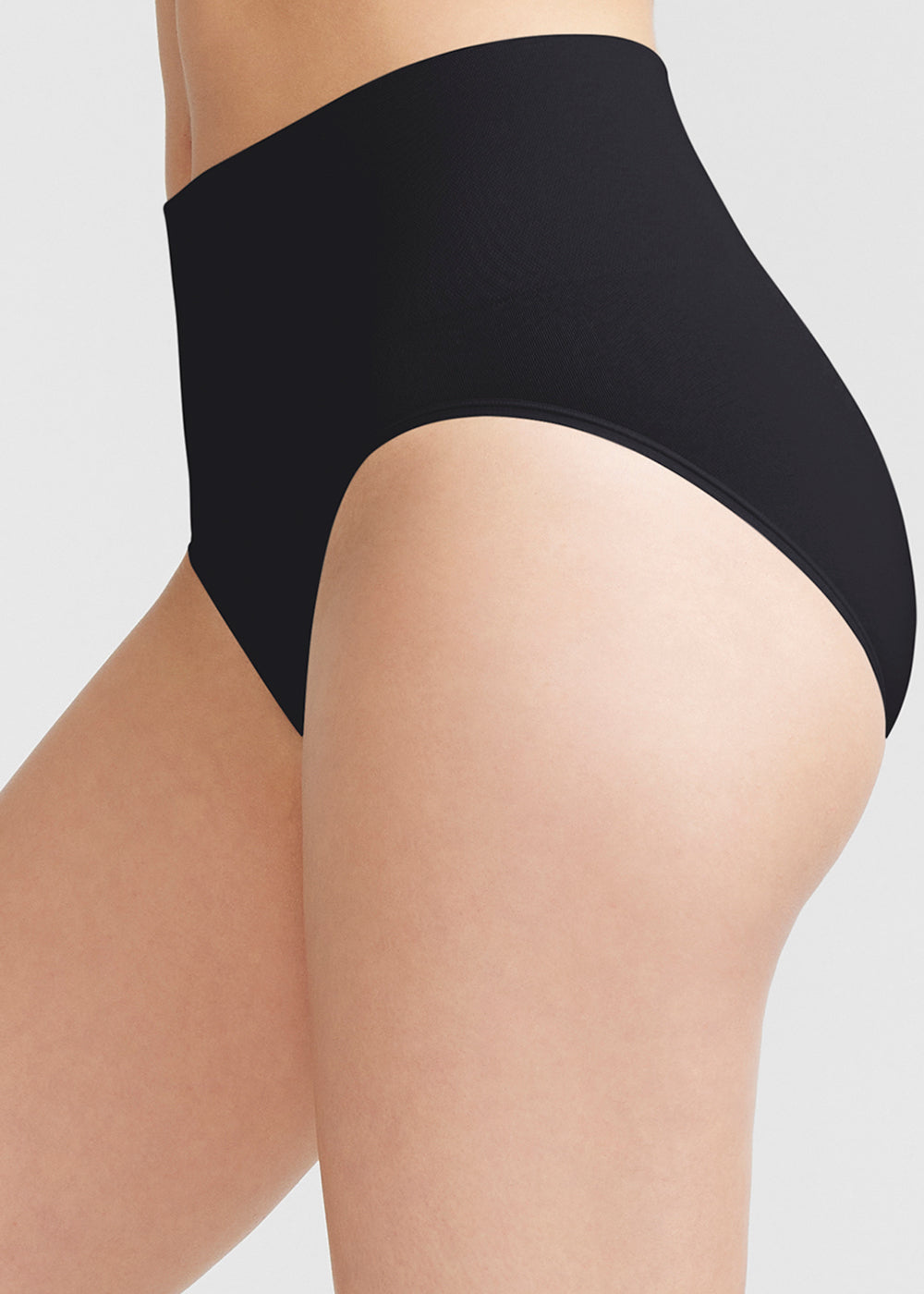 sage shaping brief - seamless in Black worn by woman standing on side Yummie