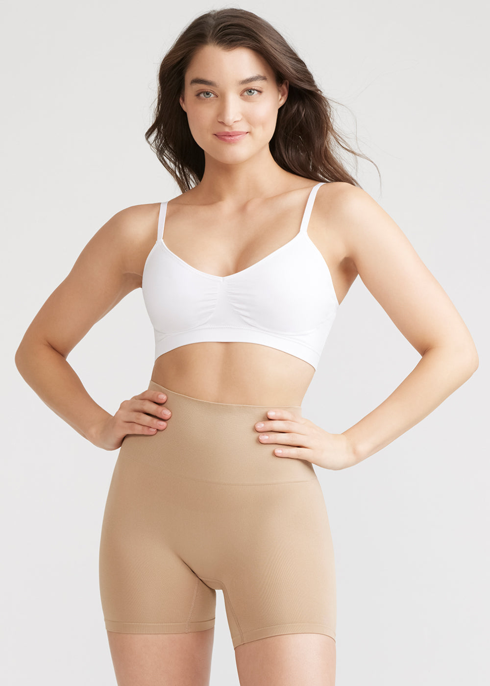 mona shaping short - seamless in Almond and  v-neck bralette - seamless in White worn by a woman facing forward with hands on waist Yummie