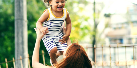 Mom tossing smiling toddler in the air