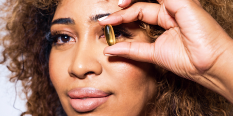Woman holding supplement pill up to her eye