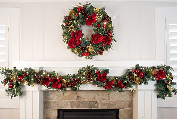 Red Magnolia Wreath and Garland Hanging Above Fireplace Mantle