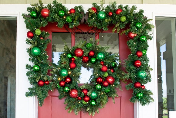 Christmas Cheer Red and Green Wreath and Garland Hanging On Front Door