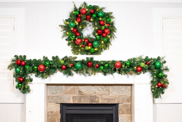 Christmas Cheer Red and Green Wreath and Garland Hanging Above Fireplace Mantle