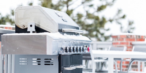 Large metal barbecue grill covered in snow