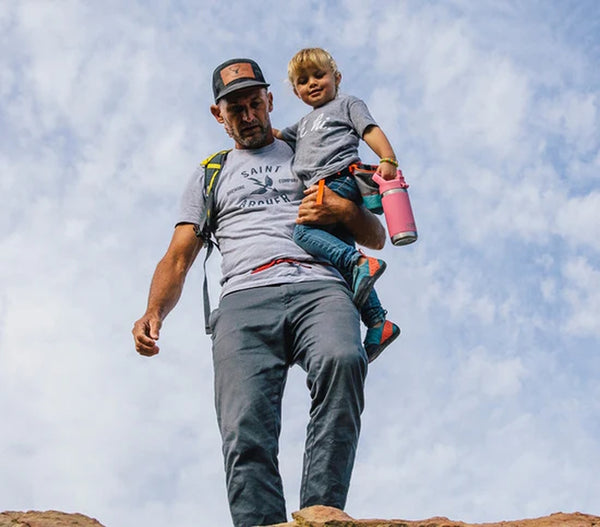A young girl with Rambler Jr. being carried by her Dad on a hiking trip