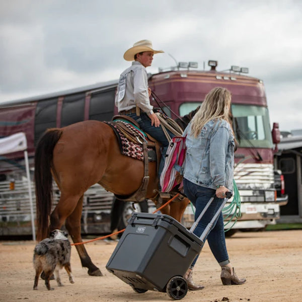 a country girl walking while pulling a wheeled Roadie 60 Cool Box