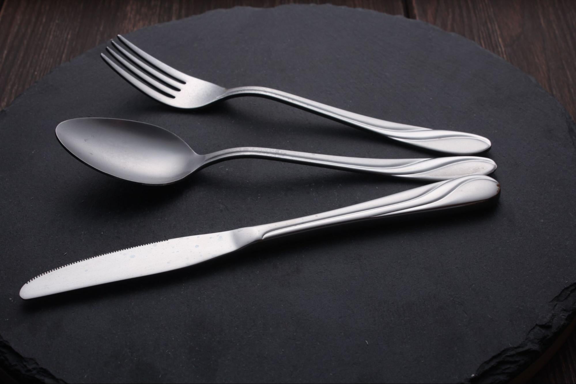 black background product photo of fork, knife, and spoon