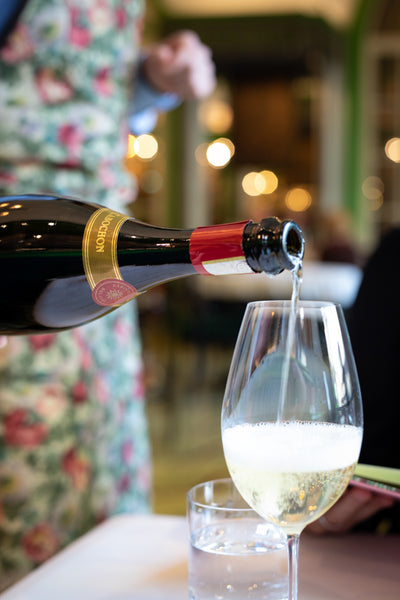 Server pouring sparkling wine at Gucci Osteria Florence, Italy
