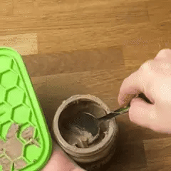 Hand scooping ice cream from a mason jar with a spoon.