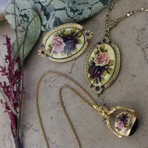 A set of gold necklaces and brooch with purple and pink roses on them