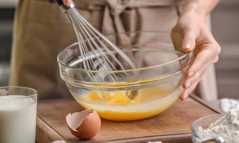 person beating eggs in a bowl