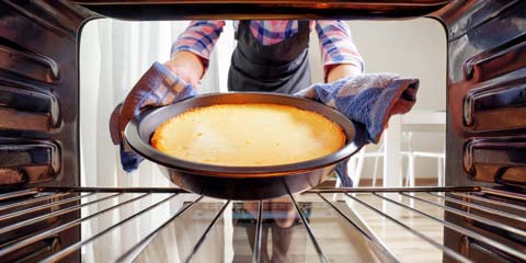 baker placing dough in the oven