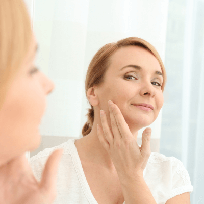 woman looking at her skin in the mirror