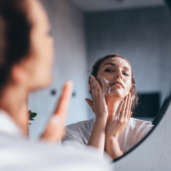 woman applying skincare in the mirror