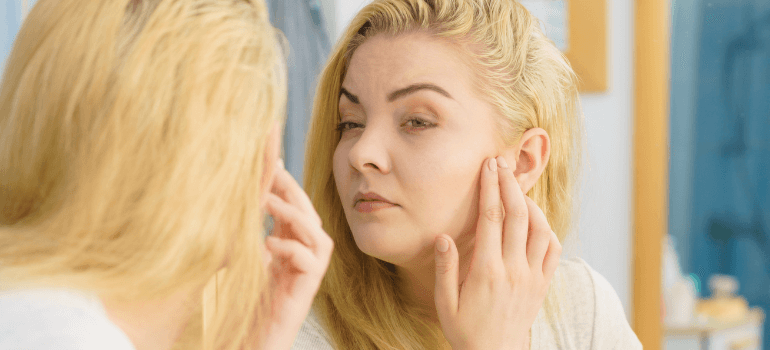 Woman looking at skin in mirror