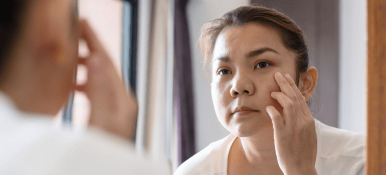 Woman looking at skin in the mirror