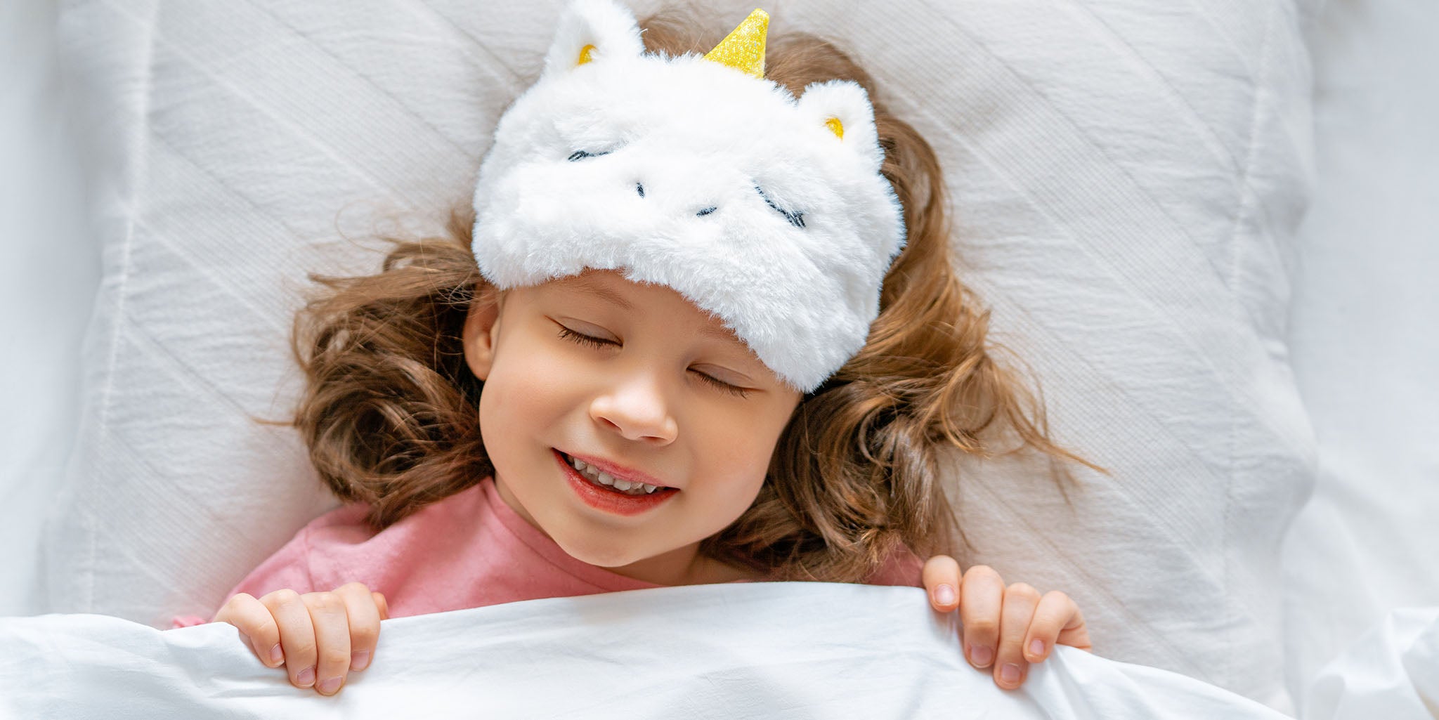 Young child falling asleep with a unicorn eye mask.