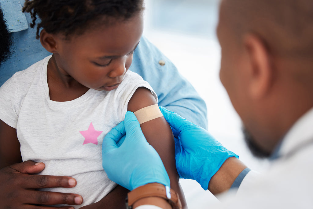 A doctor putting a bandaid on a toddler.