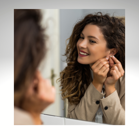 Woman looking in mirror putting on earrings